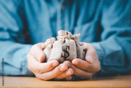 Businessman holding money bag with USD dollar sign for give dividend return profit from investment funding and stock market , Financial and accounting concept. photo