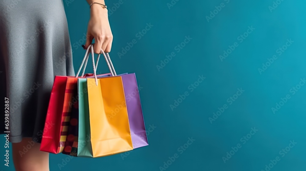 Hand holding colorful shopping bag on blank background with copy space 