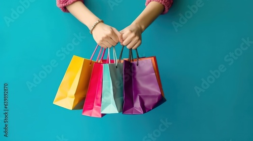 Hand holding colorful shopping bag on blank background with copy space 