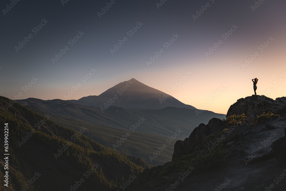 Naklejka premium Girl silhouette on a rock in a distance above the clouds in front of Teide volcano