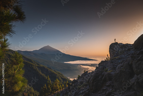 Girl silhouette on a rock in a distance above the clouds in front of Teide volcano