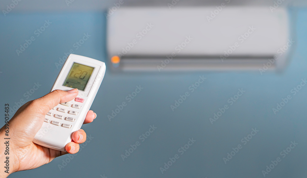 Air conditioner temperature adjustment with remote controller in room at home. Air conditioner temperature adjustment with remote controller in room at home.