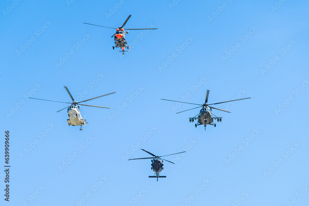 Fototapeta premium Multiple helicopters flying in formation on a clear blue day