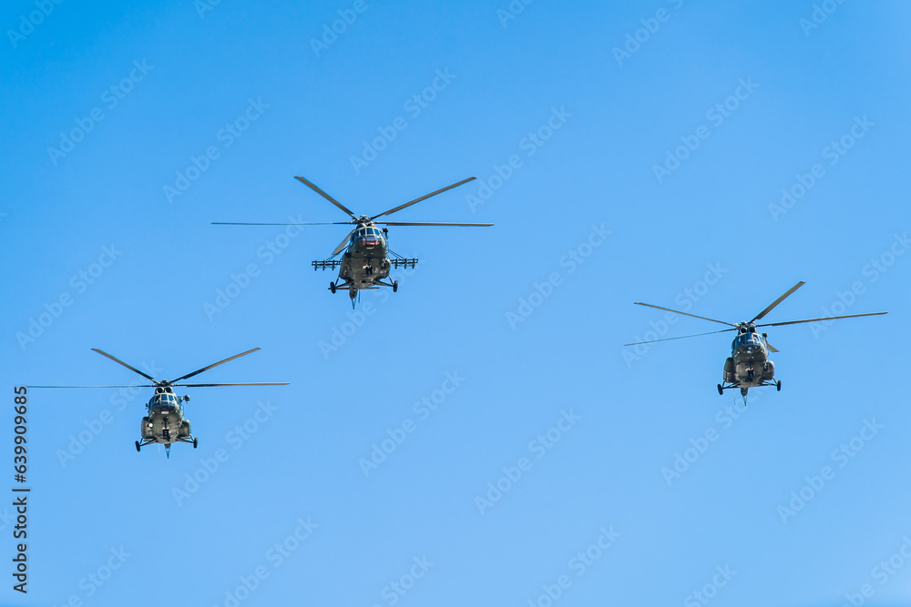 Helicopters flying in formation against a clear blue sky during daylight Helicopters flying in formation against a clear blue sky during daylight