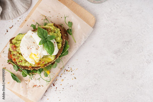 Wooden board of tasty sandwich with egg on light background