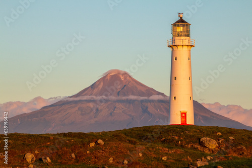 Stunning sunset view of Cape Egmont Lighthouse in front of Mt Taranaki on New Zealand's North Island