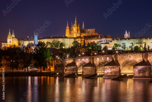 Fotografia Night time view of Charles Bridge across the Vltava River in the heart of Prague with St