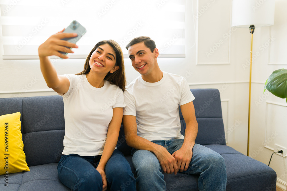 Happy couple taking a selfie wearing matching mockup tshirts