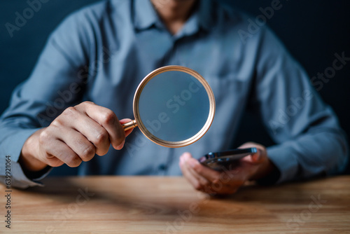 smartphone, magnifier, close up, hand, businessman, portrait, background, blue, play, formal. picture is close up to businessman, him hold smart phone and another hand hold magnifier for finding.