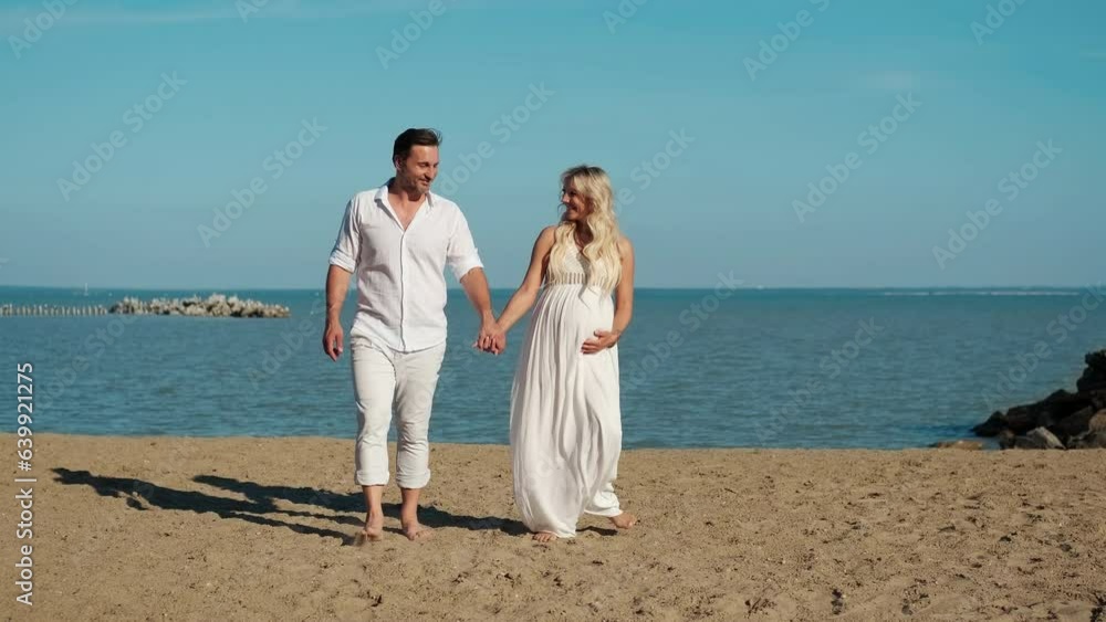 Husband and pregnant wife are walking on the ocean. Husband and pregnant wife are walking on the ocean.