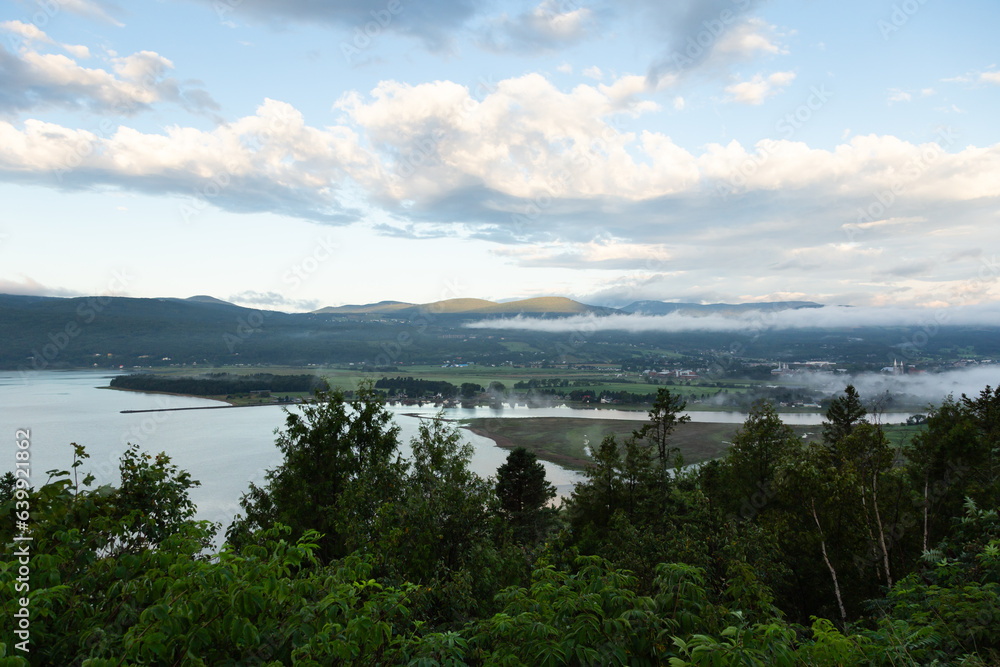 High angle view of Baie-Saint-Paul valley under low fog and the St. Lawrence River seen from point of view during a beautiful summer morning, Charlevoix, Quebec, Canada
