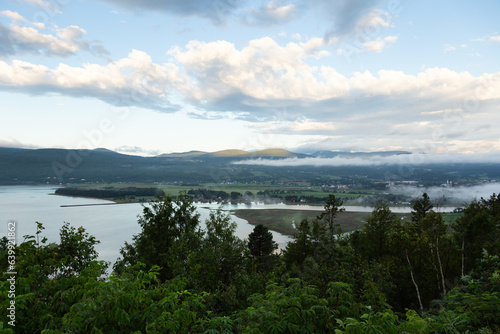 High angle view of Baie-Saint-Paul valley under low fog and the St. Lawrence River seen from point of view during a beautiful summer morning, Charlevoix, Quebec, Canada 