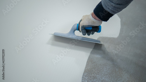 A construction worker renovates the balcony floor and spreads waterproof polyurethane resin and glue before sealing it
