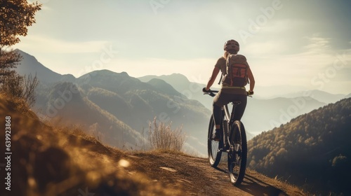 Young woman riding bicycle on beautiful mountain trail in morning
