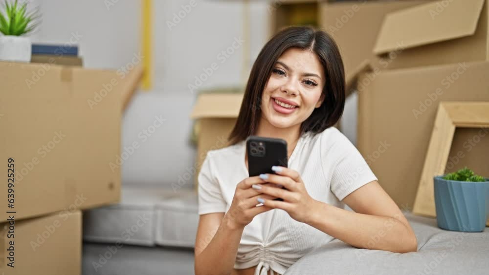 Young caucasian woman using smartphone sitting on floor with winner expression at new home