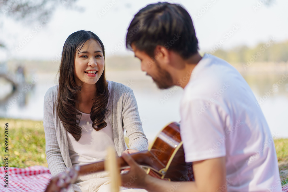 In love couple enjoying picnic time playing guitar in park outdoors Picnic. happy couple relaxing together with picnic Basket In love couple enjoying picnic time playing guitar in park outdoors Picnic. happy couple relaxing together with picnic Basket