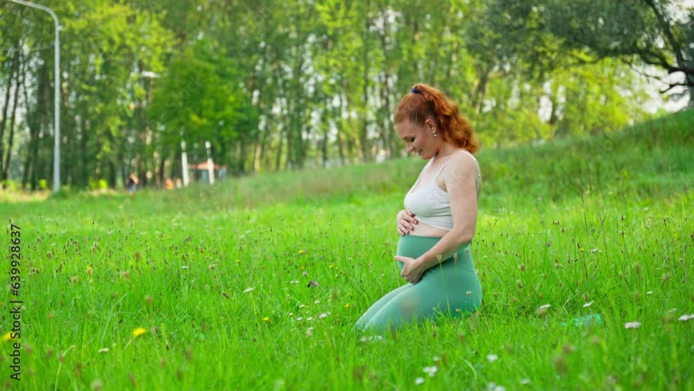 Young expecting mother holding baby in pregnant belly. Female stroking pregnant belly outdoors. Concept of mother and child health. Motherhood concept with copy space. 4K, UHD Young expecting mother holding baby in pregnant belly. Female stroking pregnant belly outdoors. Concept of mother and child health. Motherhood concept with copy space. 4K, UHD