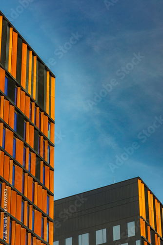 Perspective view to facade of modern corporate building with colorful reflections in windows