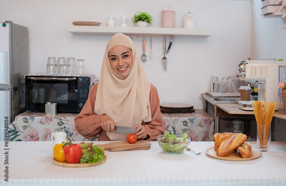 Mature muslim islamic woman in hijab mixing preparing cooking vegetable salad in the kitchen. Vegan vegetarian food concept. Mature muslim islamic woman in hijab mixing preparing cooking vegetable salad in the kitchen. Vegan vegetarian food concept.