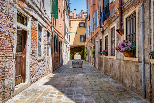 Narrow pedestrian cobblestone old alleys in Venice  Italy. Old worn out medieval buildings.