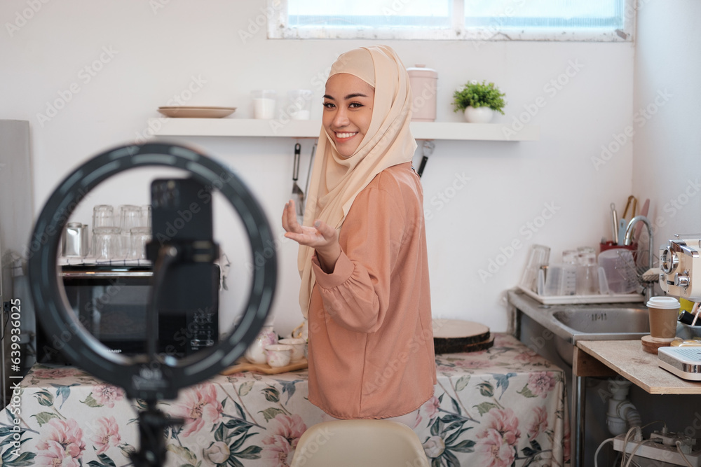 Mature Muslim woman in hijab preparing vegetable salad in kitchen while live streaming online. Vegan vegetarian food concept. Mature Muslim woman in hijab preparing vegetable salad in kitchen while live streaming online. Vegan vegetarian food concept.