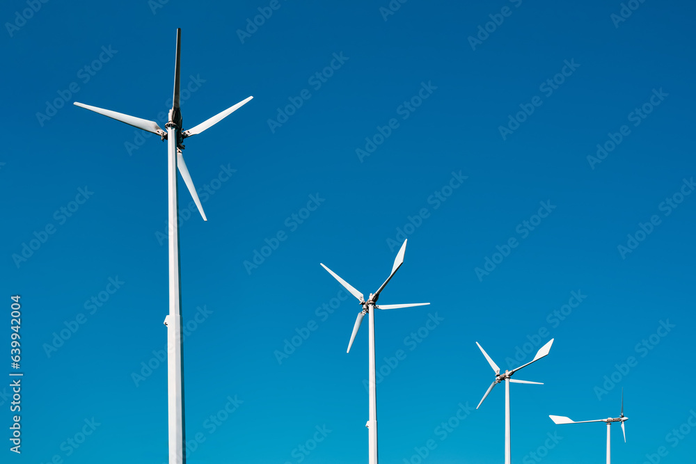 Close-up several electric wind generators against a clear blue sky. The blades do not rotate, there is no wind. Close-up several electric wind generators against a clear blue sky. The blades do not rotate, there is no wind.