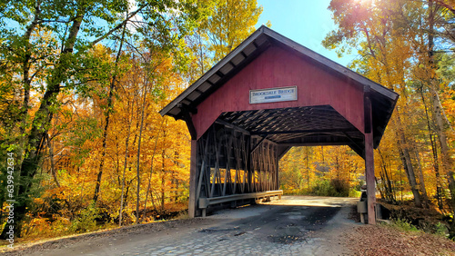 Red, wooden, covered Brookdale bridge with beautiful autumn colors, Stowe, Vermont, USA © Jenifoto
