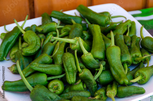 Green peppers on a plate on a wooden background
