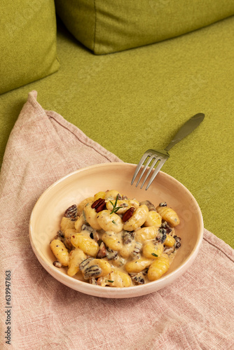 Gnocchi with brie and gorgonzola cheese, speck and nuts. Italian dish.