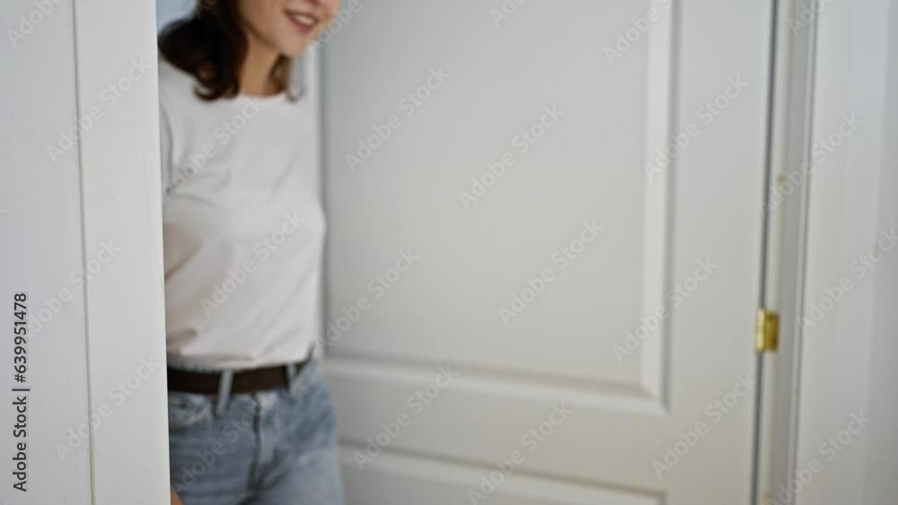 Young woman opening door with surprise expression at home Young woman opening door with surprise expression at home