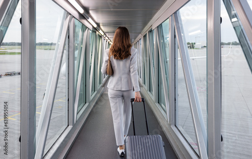 Businesswoman boarding plane walking in the bridge connecting the airport gate and the plane