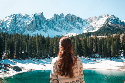 Woman staring at Lago di Carezza in Dolomites during a winter day