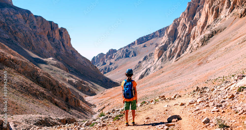 little boy with a backpack stands along the path against the backdrop of the mountains. travel with children to the mountains. Turkey. Aladaglar. little boy with a backpack stands along the path against the backdrop of the mountains. travel with children to the mountains. Turkey. Aladaglar.
