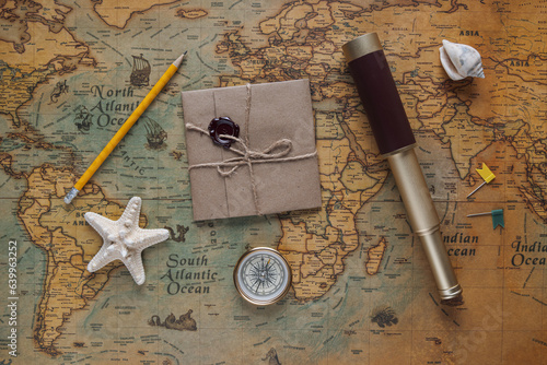 spyglass, a compass, a starfish, a pencil and a wax seal package with space for text or logo lie on a vintage map. View from above