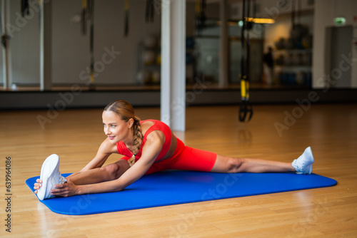 Woman doing stretching exercise on the floor in a gym