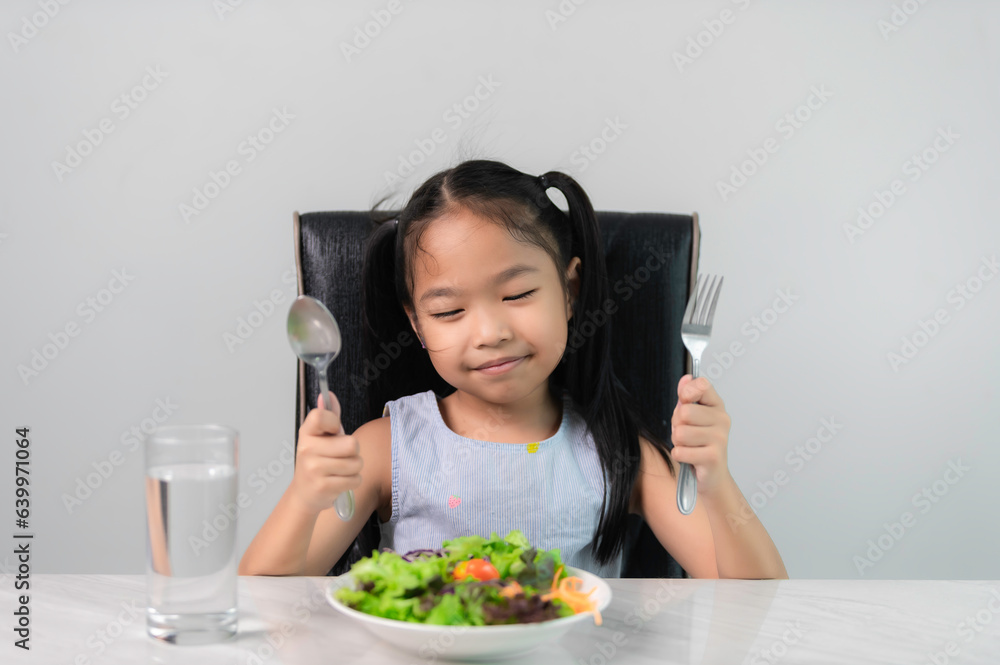Little asian cute girl to eat healthy vegetables.Nutrition and healthy eating habits for kids concept.Children happy and like to eat vegetables. Little asian cute girl to eat healthy vegetables.Nutrition and healthy eating habits for kids concept.Children happy and like to eat vegetables.