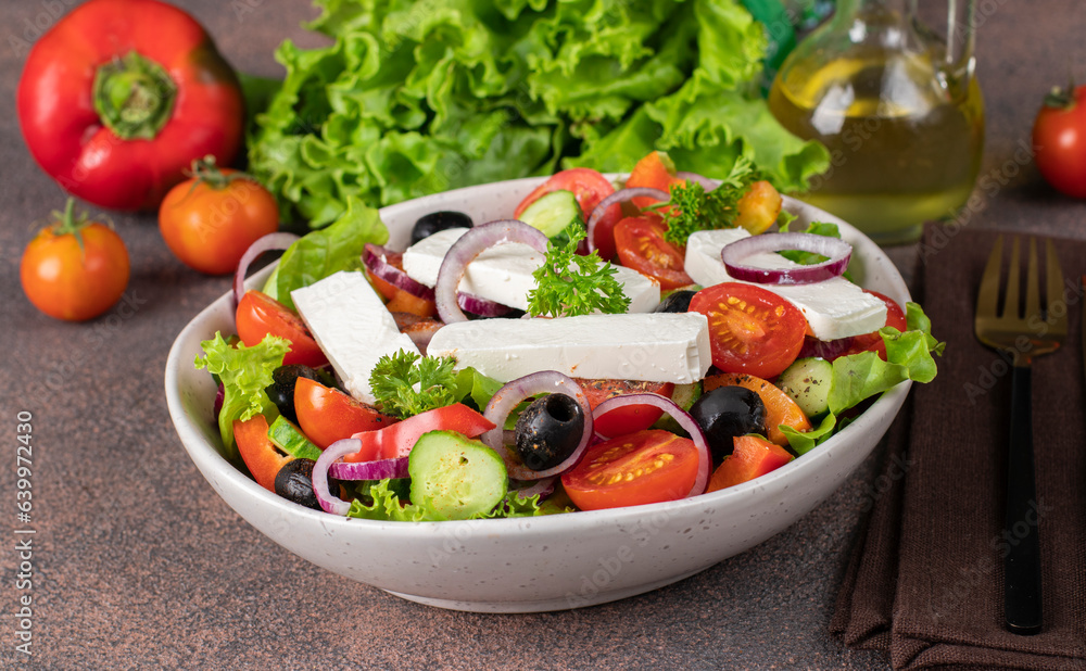 Classic Greek salad from tomatoes, cucumbers, sweet pepper, olives, red onion and feta cheese in white bowl, Close up