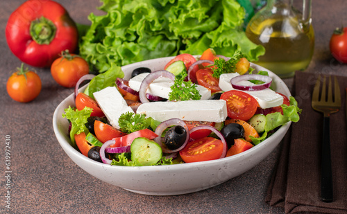 Classic Greek salad from tomatoes, cucumbers, sweet pepper, olives, red onion and feta cheese in white bowl, Close up
