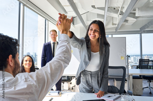 Happy young Indian woman worker giving male colleague high five celebrating good team work results, financial success in professional teamwork at diverse coworkers group office meeting.
