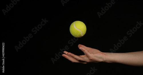 Hand of Woman Throwing a Ball of tennis against Black Background