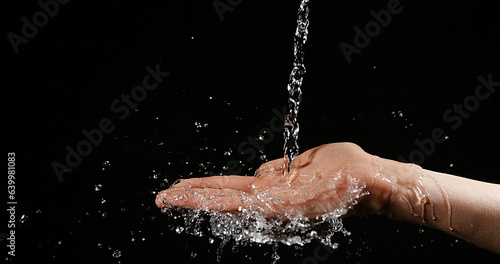 Hands of Woman and Water against Black Background