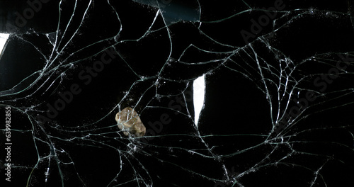 Stone breaking Pane of Glass against Black Background photo