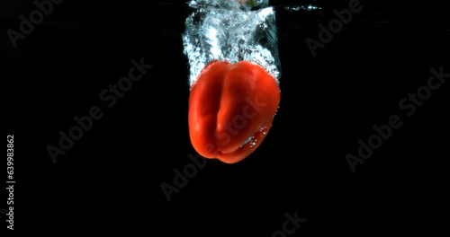 Red Sweet Pepper, capsicum annuum, Vegetable falling into Water against Black Background