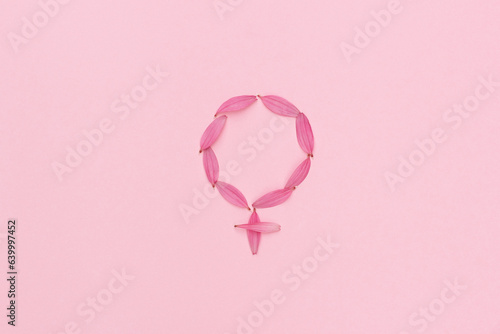 Female gender symbol made with pink flower petals on pink abstract background. Woman medicine and health concept: hormones, menopause, pms, menstruation or estrogen level disorder.