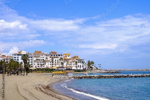 Sandstrand mit Palmen und Sonnenschirmen in der Nähe des Luxus-Yachthafens Puerto Banús in der Nähe von Marbella, Málaga, Andalusien, Spanien