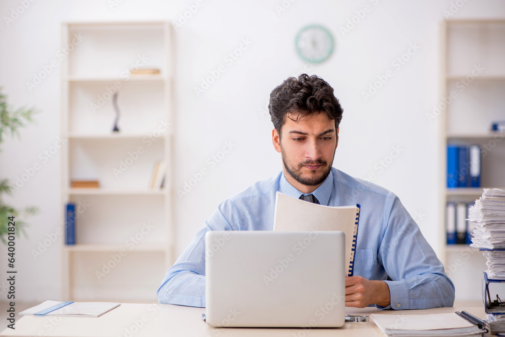 Young male employee and too much work in the office Young male employee and too much work in the office