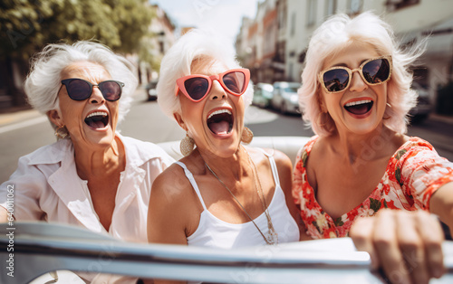 Company of three elderly girlfriends of pensioners ride a cabrio car together and have fun