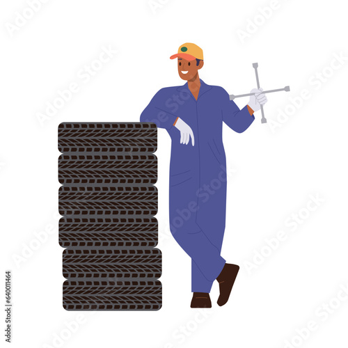 Auto mechanic holding wrench or jack-screw standing nearby tire stack isolated on white background
