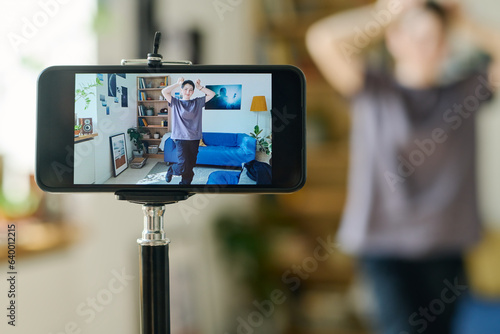 Focus on smartphone screen with dancing teenage girl in casualwear showing dance exercise to online audience during livestream