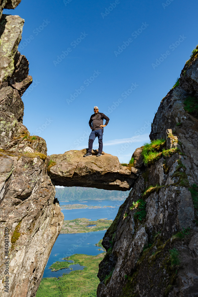 Active Senior tourist man hiking at the beautiful Rock stuck in mountains Djevelporten. Norway. Happy pensioner climbing a mountain. Scandinavian tourism. Enjoying the outdoor leisure activity